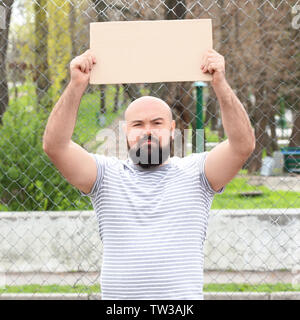 Protestieren junge Mann holding Stück Pappe mit Platz für Text auf der Straße Stockfoto