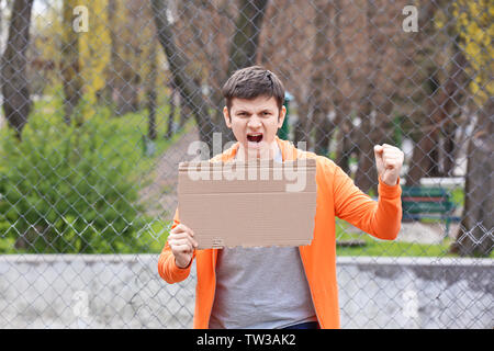 Protestieren junge Mann holding Stück Pappe mit Platz für Text auf der Straße Stockfoto