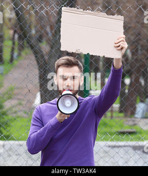 Protestieren junge Mann holding Stück Pappe mit Platz für Text und Megaphon auf der Straße Stockfoto