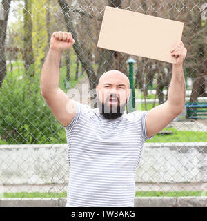 Protestieren junge Mann holding Stück Pappe mit Platz für Text auf der Straße Stockfoto