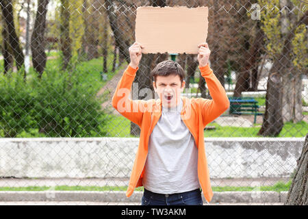 Protestieren junge Mann holding Stück Pappe mit Platz für Text auf der Straße Stockfoto