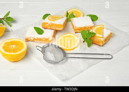 Leckere Lemon Pie bars und Sieb mit Puderzucker auf hölzernen Tisch Stockfoto