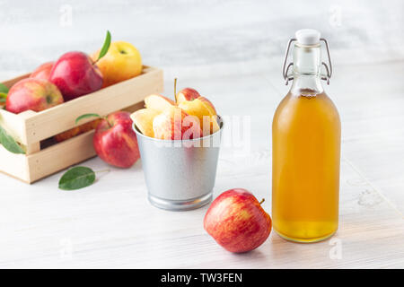 Gesunde Bio-lebensmittel. Apfelessig in Glas und Flasche frische rote Äpfel auf einem hellen Hintergrund. Stockfoto