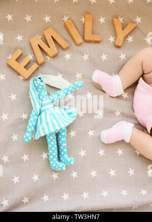 Beine von niedlichen Baby, Spielzeug und Wort EMILY aus Holz Buchstaben auf dem Bett. Auswahl name Konzept Stockfoto