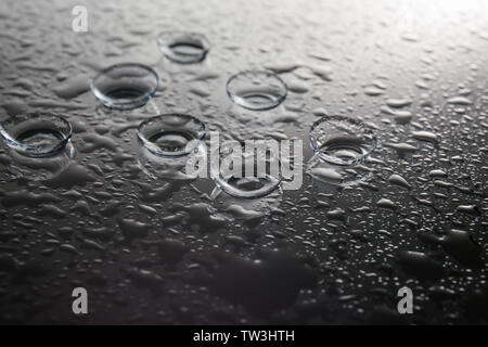 Kontaktlinsen und Tropfen Wasser auf grauem Hintergrund Stockfoto