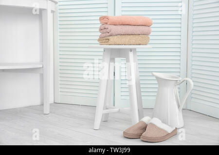 Schönen Komposition mit sauberen Handtücher, Hausschuhe und Kanne in hellem Zimmer Stockfoto