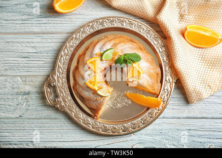 Fach mit köstlichen Kuchen geschnitten und Zitrusfrüchte auf hölzernen Tisch Stockfoto