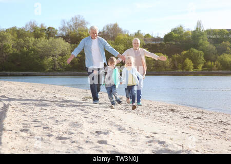 Glückliche Großeltern spielen mit kleinen Kindern am Flussufer Stockfoto