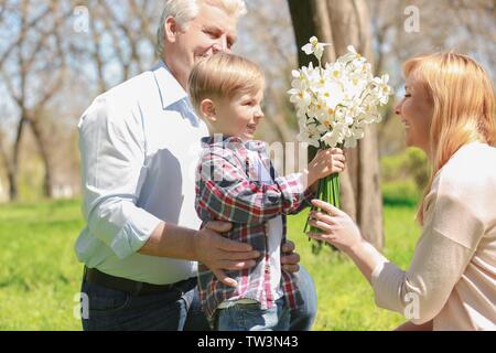 Süße kleine Jungen mit Großvater, Blumenstrauß zu seiner Großmutter in Spring Park an einem sonnigen Tag Stockfoto