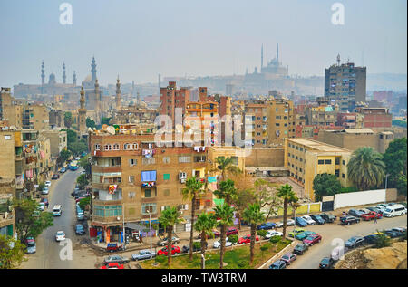 Die minarette der Al-Rifai, die Sultan Hassan Moschee und die Alabaster Moschee von Kairo Zitadelle sind hinter den staubigen Hochhäuser von Al Sayeda Zeinab dis gesehen Stockfoto