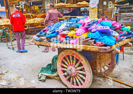 Kairo, Ägypten, 22. Dezember 2017: Die vintage Holz Karre in der Straße von Souq als Sebaeyin Markt mit Haufen von bunten Gummi Clogs, am 22. Dezember in C Stockfoto