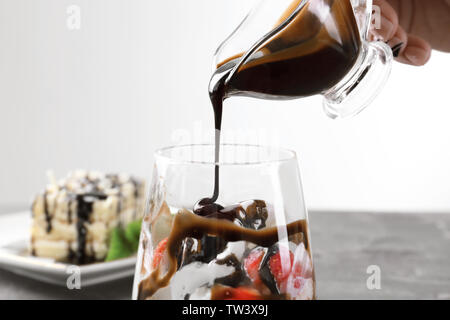 Frau gießen Schokoladensauce auf Glas mit leckeren Nachtisch, Nahaufnahme Stockfoto