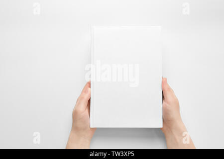 Weibliche Hände halten geschlossenes Buch mit Abdeckung auf hellen Hintergrund Stockfoto