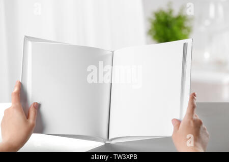 Weibliche Hände halten Buch mit leeren Seiten geöffnet auf hellen Hintergrund Stockfoto