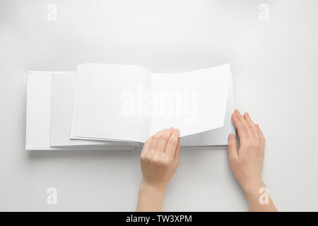 Weibliche Hände halten Buch mit leeren Seiten auf weißem Hintergrund Stockfoto