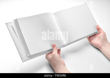 Weibliche Hände halten Buch mit leeren Seiten auf weißem Hintergrund Stockfoto