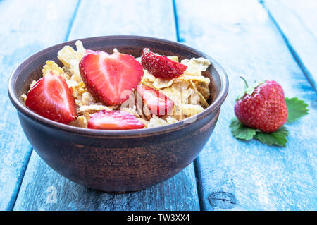 Frisches hausgemachtes Müsli, Müsli mit Erdbeeren in eine Platte auf einem blauen Hintergrund, selektiver Fokus Stockfoto