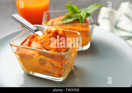 Glasschalen mit leckeren Karotte souffle und Löffel auf Platte, Nahaufnahme Stockfoto