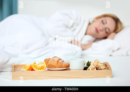 Fach mit Frühstück im Hotel Zimmer und schlafende Frau auf Hintergrund Stockfoto