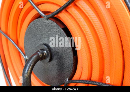 Schönes, sauberes, orange Schlauch aufgerollt ordentlich auf eine Schlauchhaspel Stockfoto