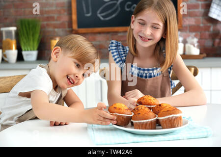 Junge und Mädchen essen lecker Muffins in der Küche. Kochkurse Konzept Stockfoto