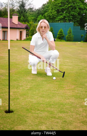 Schöne junge Frau spielen Golf auf Kurs im Sommer Tag