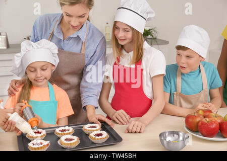 Gruppe von Kindern und Lehrer Vorbereitung Dessert während Kochkurse Stockfoto