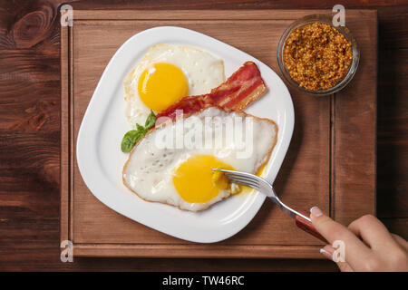 Frau Essen über einfach Eier mit Speck am Tisch Stockfoto