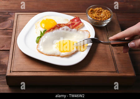 Frau Essen über einfach Eier mit Speck am Tisch Stockfoto