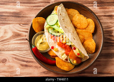 Lecker Fisch taco auf Platte mit Soße und Chips auf Holz- Hintergrund Stockfoto