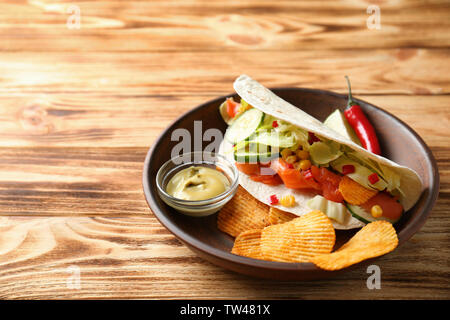Lecker Fisch taco auf Platte mit Soße und Chips auf Holz- Hintergrund Stockfoto