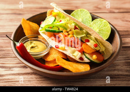 Lecker Fisch taco auf Platte mit Soße und Chips auf Holz- Hintergrund Stockfoto