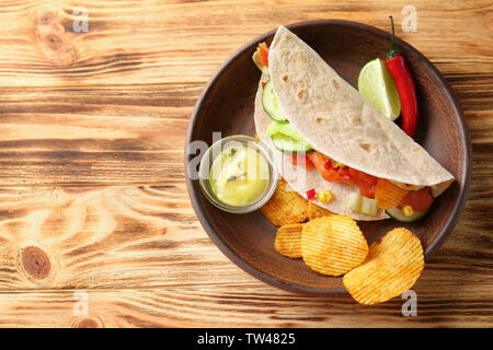 Lecker Fisch taco auf Platte mit Soße und Chips auf Holz- Hintergrund Stockfoto