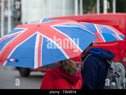 London, Großbritannien. 18. Juni 2019. Touristen und Einheimische, die das Londoner Schutz gegen die anhaltenden Regenfälle in Central London. Der Union Jack Dach scheint sehr beliebt zu sein. Credit: JoeKuis/Alamy Stockfoto
