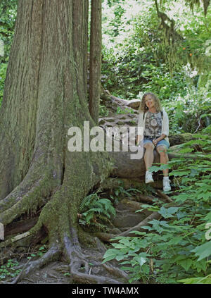 Eine junge Frau nimmt einen Bruch an einem Wanderweg. Stockfoto