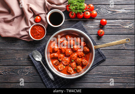 Topf mit leckeren Frikadellen in Tomatensoße auf Tisch Stockfoto