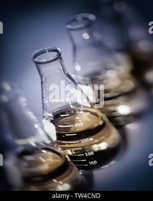 Selektiver Fokus verzerrt Weitwinkel Labor Flash mit hellen grünen Lösung auf gelber Lichthof mit weißem Hintergrund Stockfoto