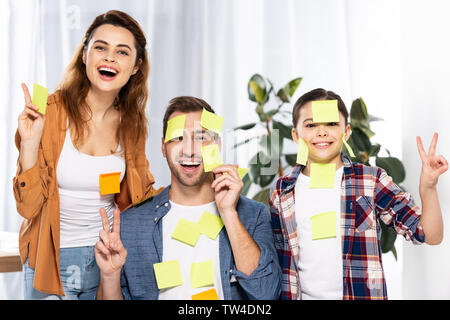Fröhliche Eltern und niedlichen Kind in Kurznotizen angezeigt Frieden Zeichen Stockfoto