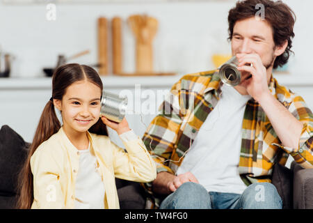 Gerne Vater am Telefon sprechen und fröhliche Tochter zu Hause hören Stockfoto