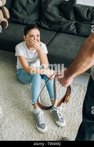 Ansicht von oben der Vater mit Gürtel und Tochter sitzen auf dem Boden Stockfoto