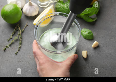 Frau Vorbereitung cremige Sauce für Fisch taco in Blender bowl am Küchentisch Stockfoto