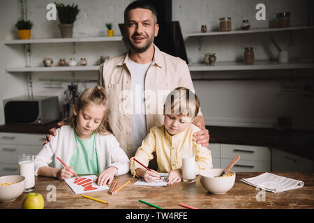 Gerne Vater in der Nähe von adorable Kinder Zeichnung Vatertag Grußkarten am Küchentisch Stockfoto
