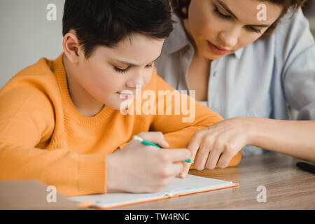 Schöne Frau helfen aufmerksam Sohn Schularbeiten zu Hause Stockfoto