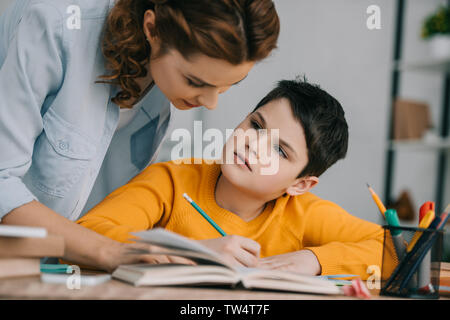 Schöne Frau helfen adorable Sohn Schularbeiten zu Hause Stockfoto