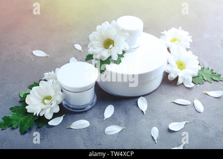 Gläser mit Creme und Kamillenblüten auf Tisch Stockfoto