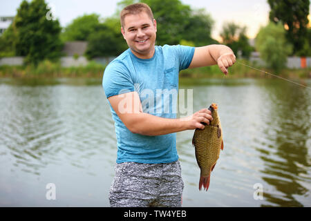 Glückliche Menschen mit frisch gefangenen Fisch am Ufer Stockfoto