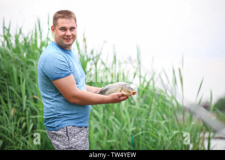 Glückliche Menschen mit frisch gefangenen Fisch am Ufer Stockfoto