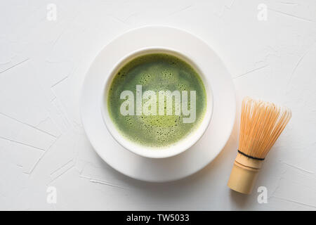 Zeremonie traditionelle Green Matcha Tee in der Schüssel und bambusbesen auf weißem Beton. Ansicht von oben. Stockfoto