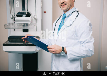 Teilansicht der Arzt holding Zwischenablage beim Stehen bei x-ray Maschine Stockfoto