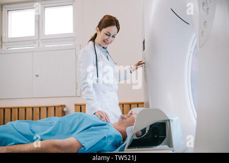 Hübsche junge radiologe Vorbereitung Mann für die Tomographie Diagnose im MRT-Gerät Stockfoto